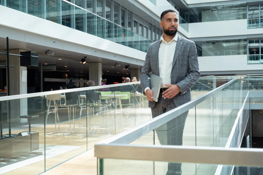 Oussama loopt bij een balustrade op kantoor bij de ADR