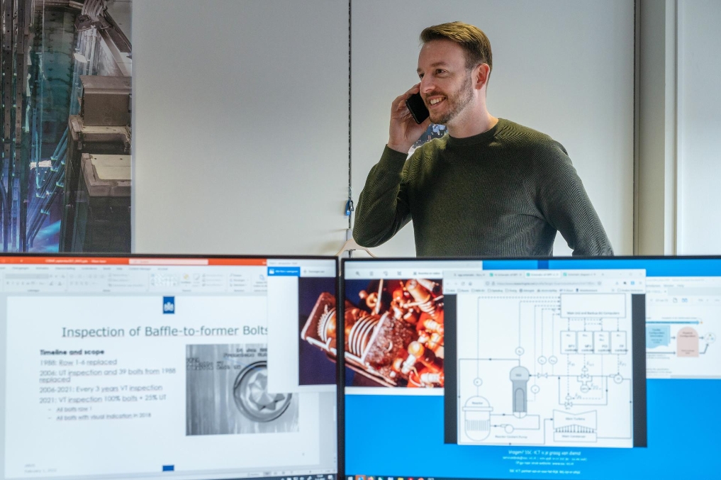 Eric Schreurs op kantoor met telefoon in hand bij de Autoriteit Nucleaire Stralingsbescherming