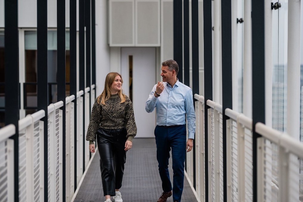 Vincent loopt met een collega door de gang bij IenW. Hij is plaatsvervangend afdelingshoofd ontwikkeling bij het ministerie