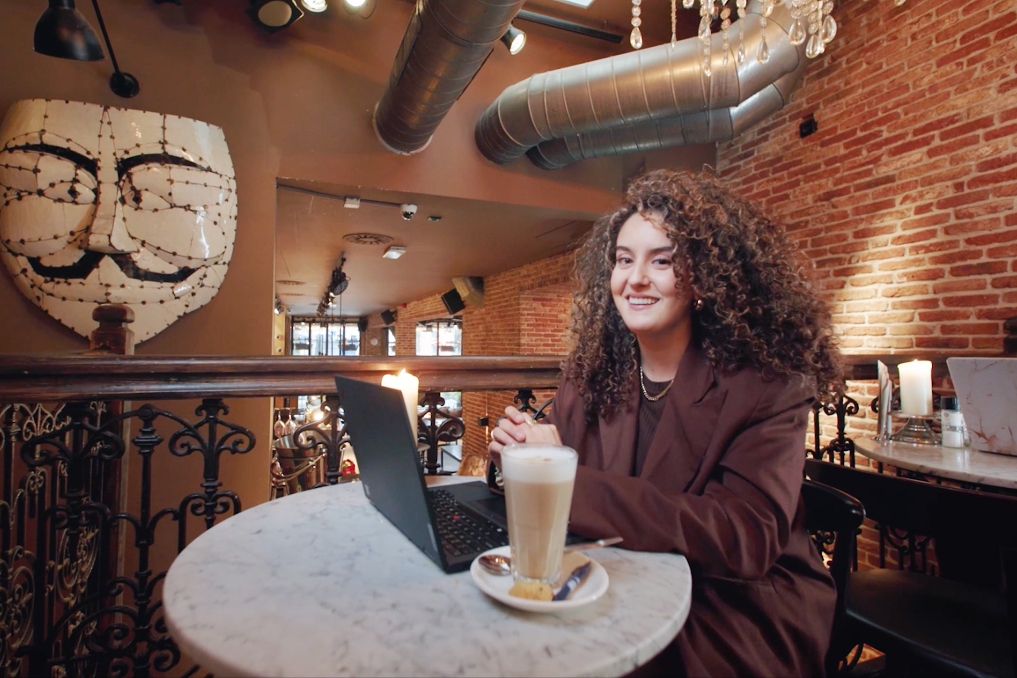 Saloua zit in een café te werken met een kop koffie