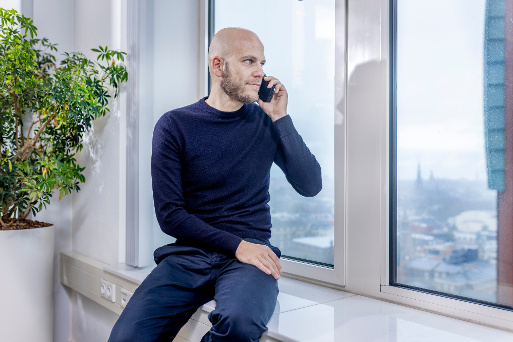 Koen Orbons, seniorjurist bij de Rijksoverheid, bellend voor een raam met ver uitzicht