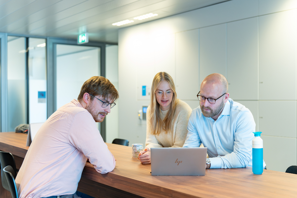 3 collega-wetgevingsjuristen bij de Rijksoverheid achter de laptop in gesprek